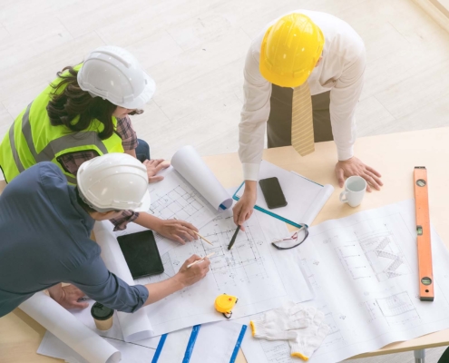 Team of engineers and architects working, planing, measuring layout of building blueprints in construction site. top view_