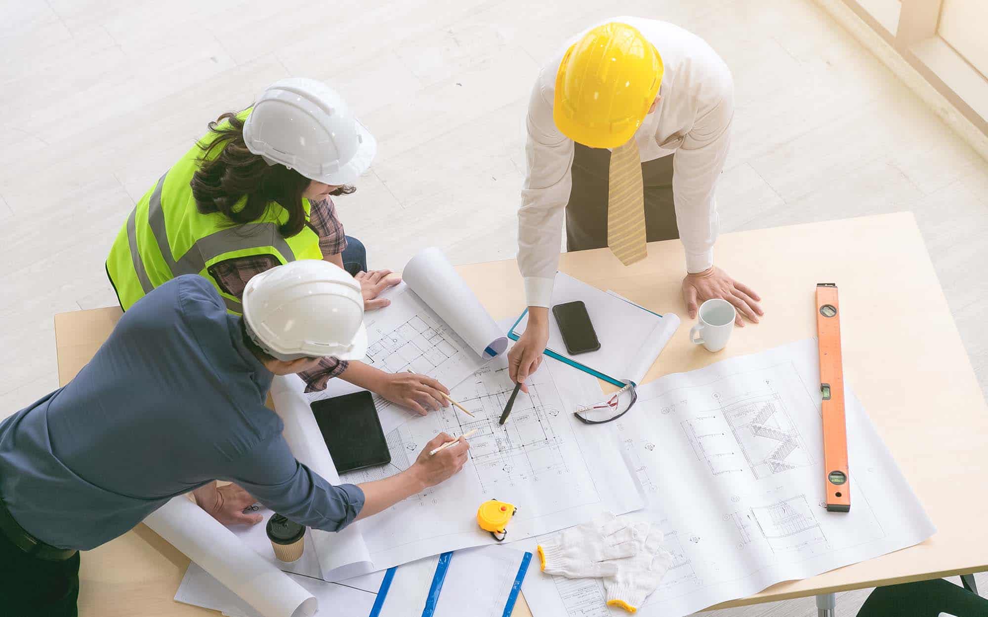 Team of engineers and architects working, planing, measuring layout of building blueprints in construction site. top view_