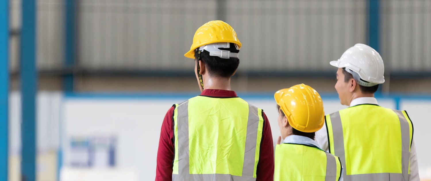 A row of three construction workers wearing hard hats