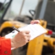 Side view of a construction worker recording data on a clipboard